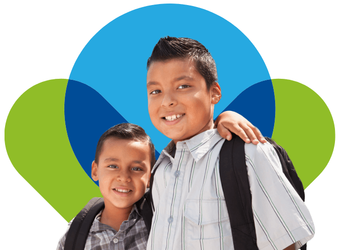 Two smiling boys wearing backpacks and striped shirts stand close together, one boy’s arm around the other, in front of a colorful abstract background inspired by the vibrant patterns found at Michigan Central Station.