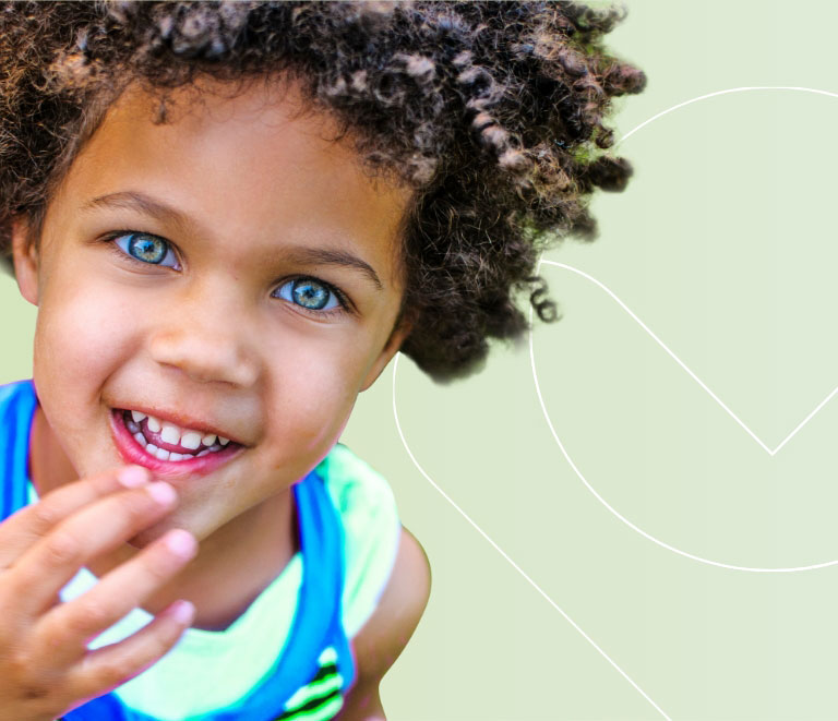 A young child with curly hair and bright blue eyes smiles at the camera, wearing a blue and green outfit, against a light green background with subtle white line patterns.